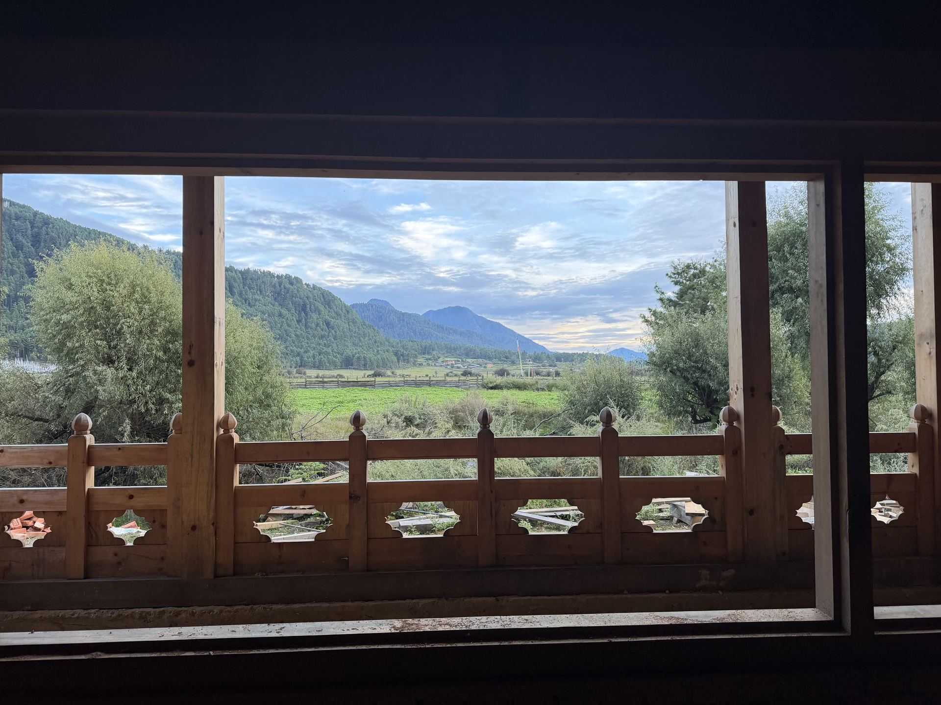 The Khotokha valley floor and its ridgeline seen through a carved traditional Bhutanese timber balcony