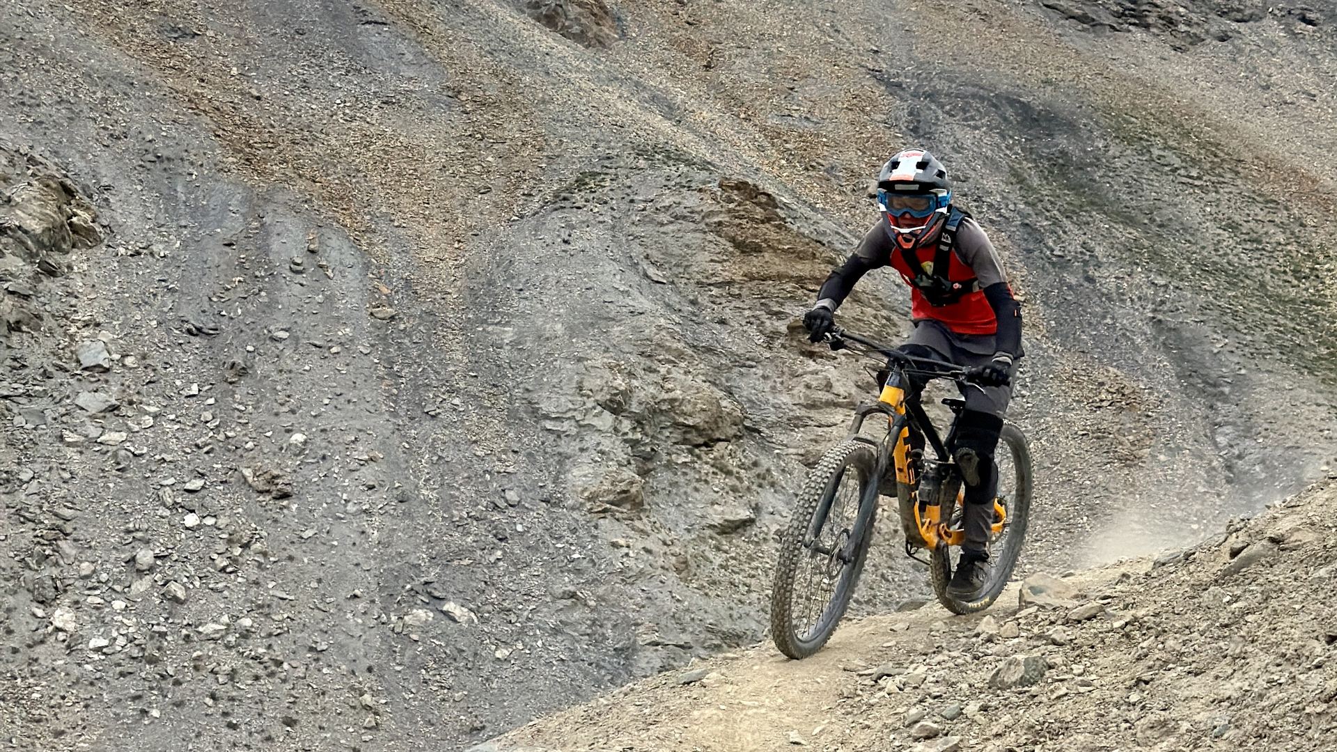 Mountain biker cornering on scree below Zangla's royal palace in Zanskar
