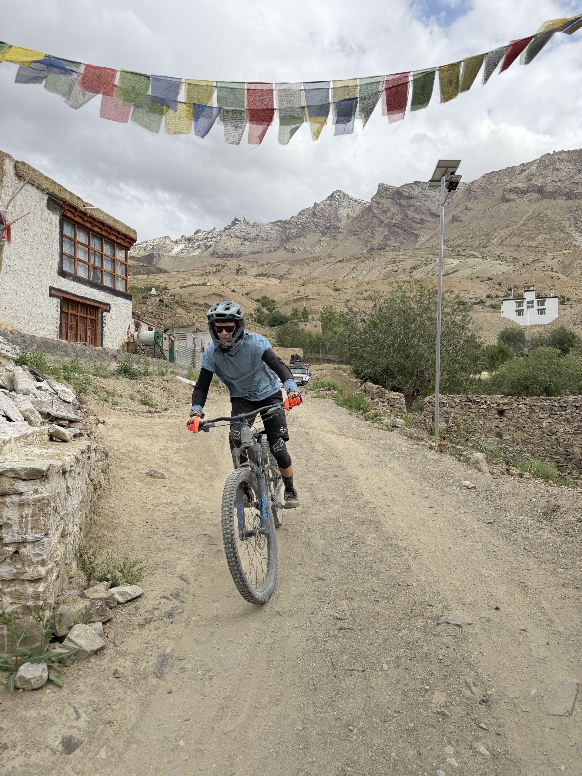 Riders rolling into a Zanskar village under prayer flags